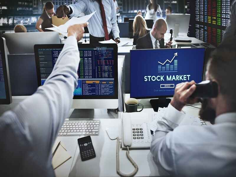 "Stock market professionals analyzing data on computer screens, representing the influence of financial platforms like FintechZoom on investment decisions and stock performance."